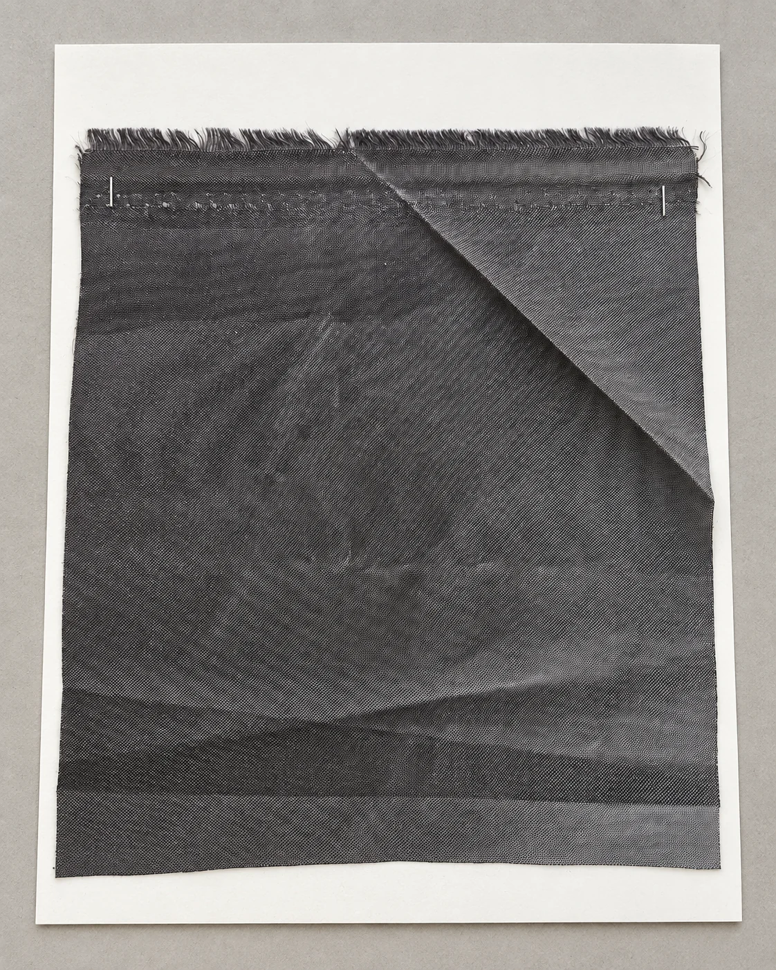 Surface and folded edge of a grey fabric swatch